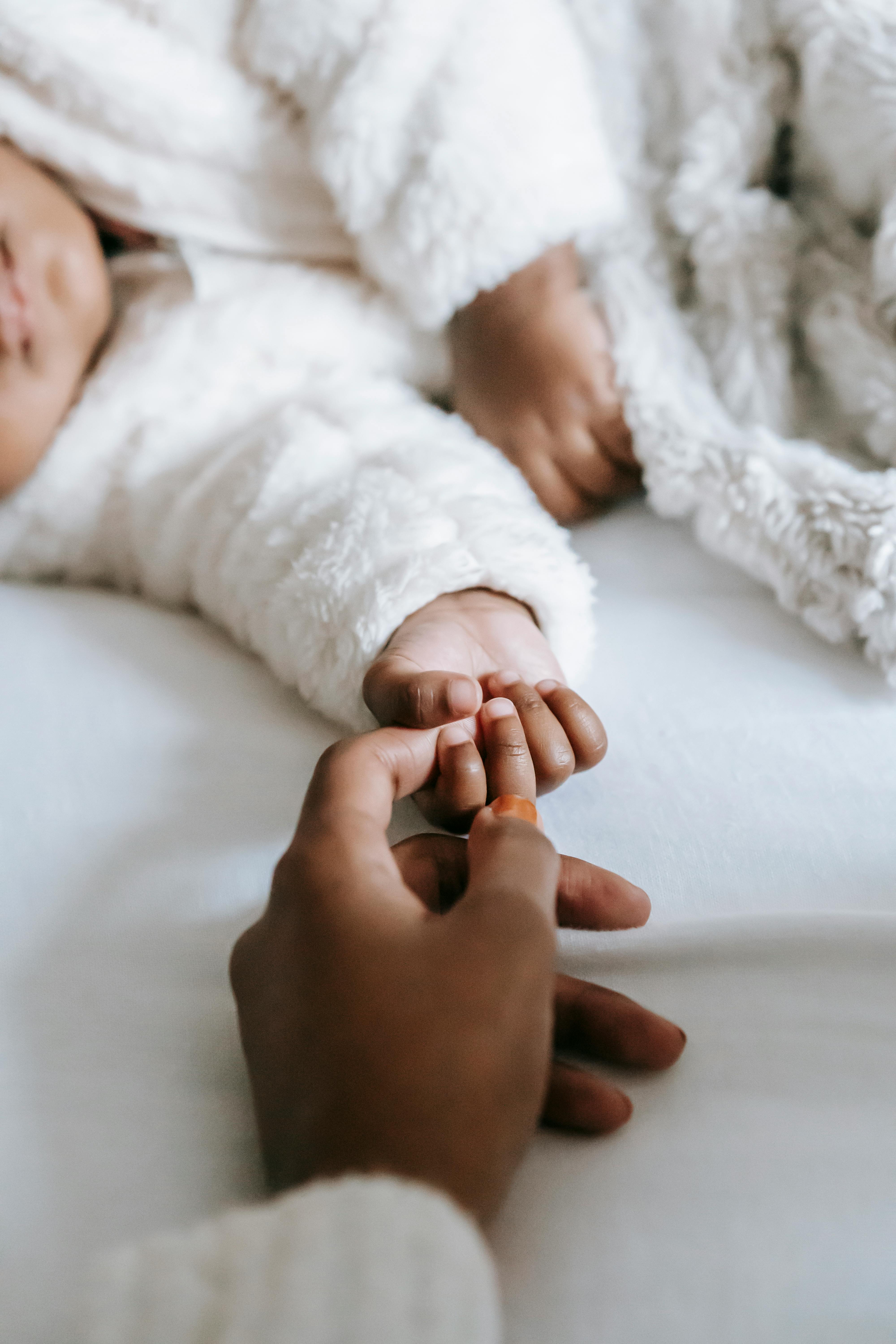 An educator from Picolini's Place holding a child's hand